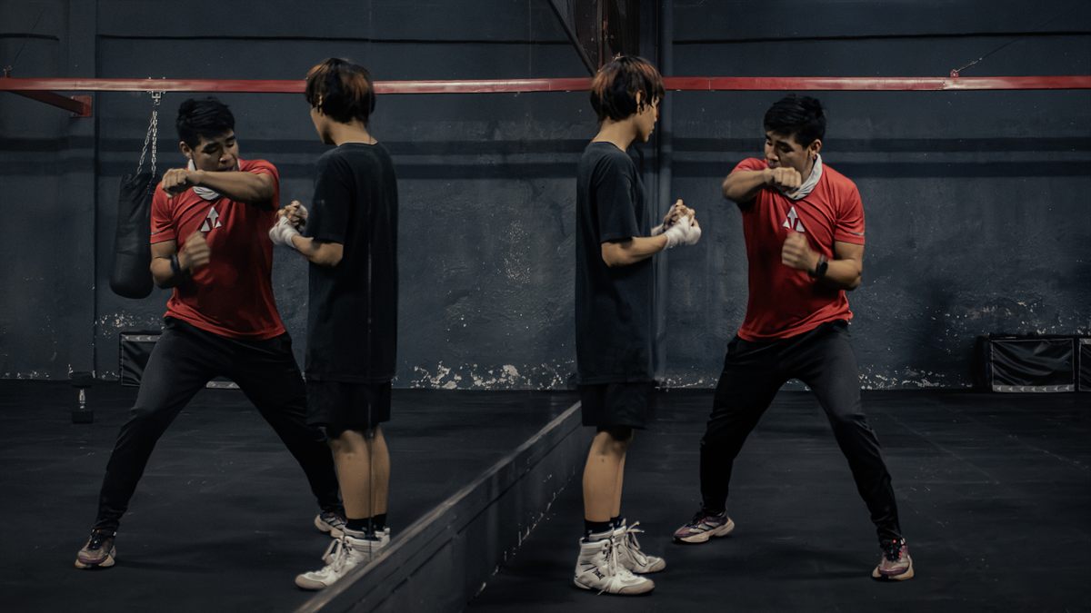 Coach de boxeo enseñando técnica frente a un espejo